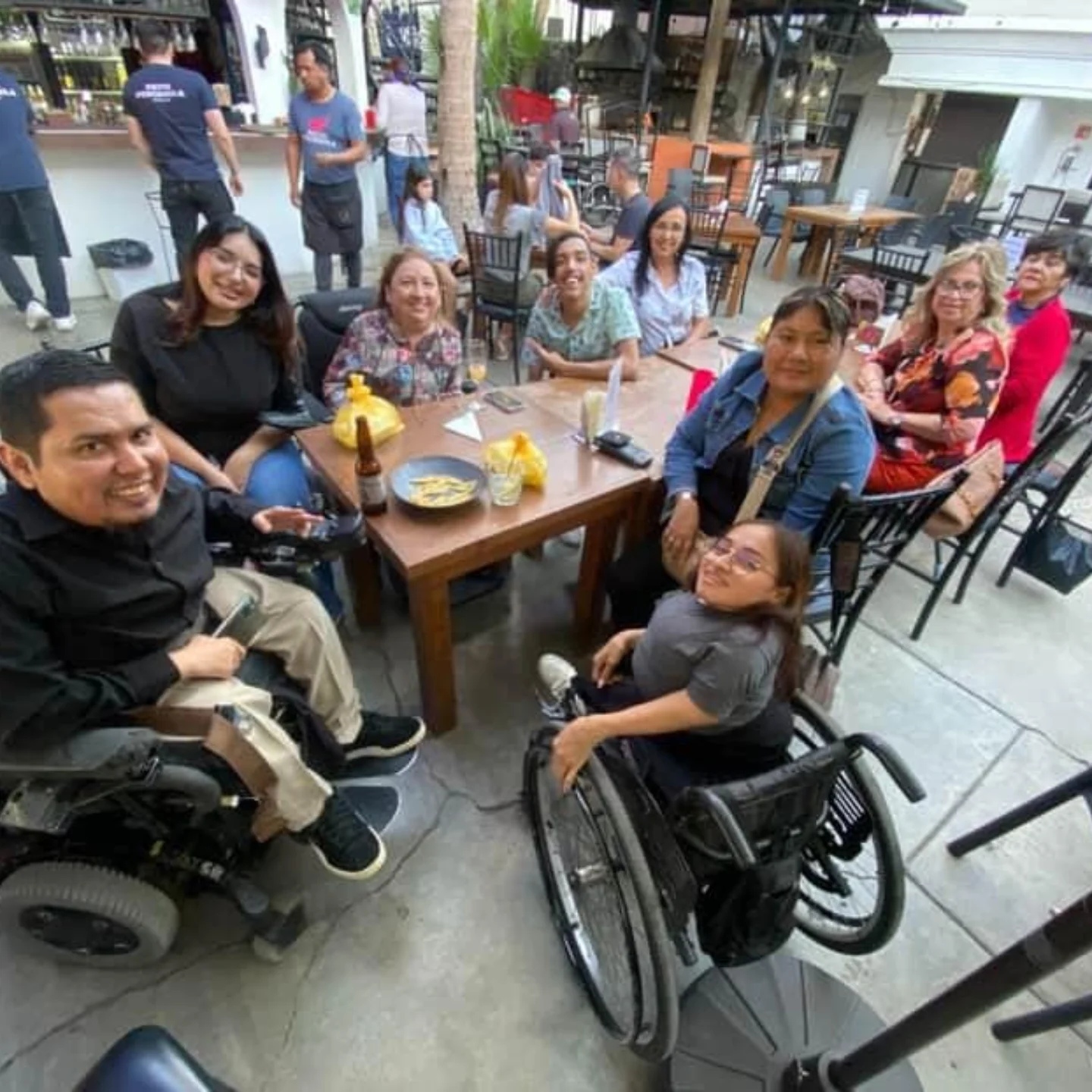 Un grupo de personas con y sin discapacidad, alrededor de una mesa en un restaurante