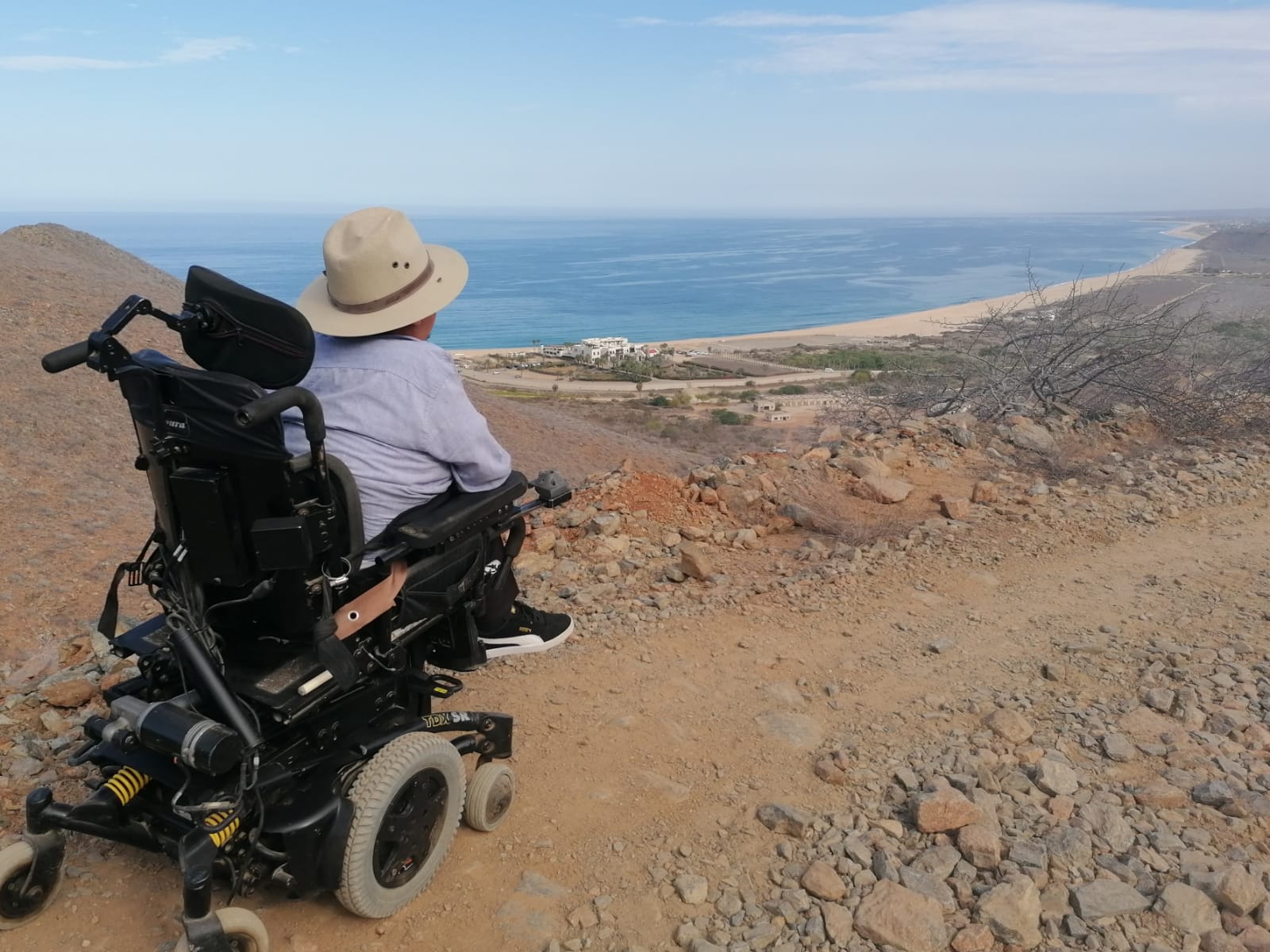 Una persona en silla de ruedas viendo la bahía desde un mirador en un cerro.